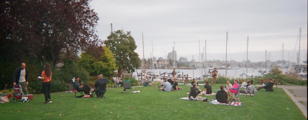 Offline Reading Rave A photo of people sitting on a field overlooking a marina on the water.